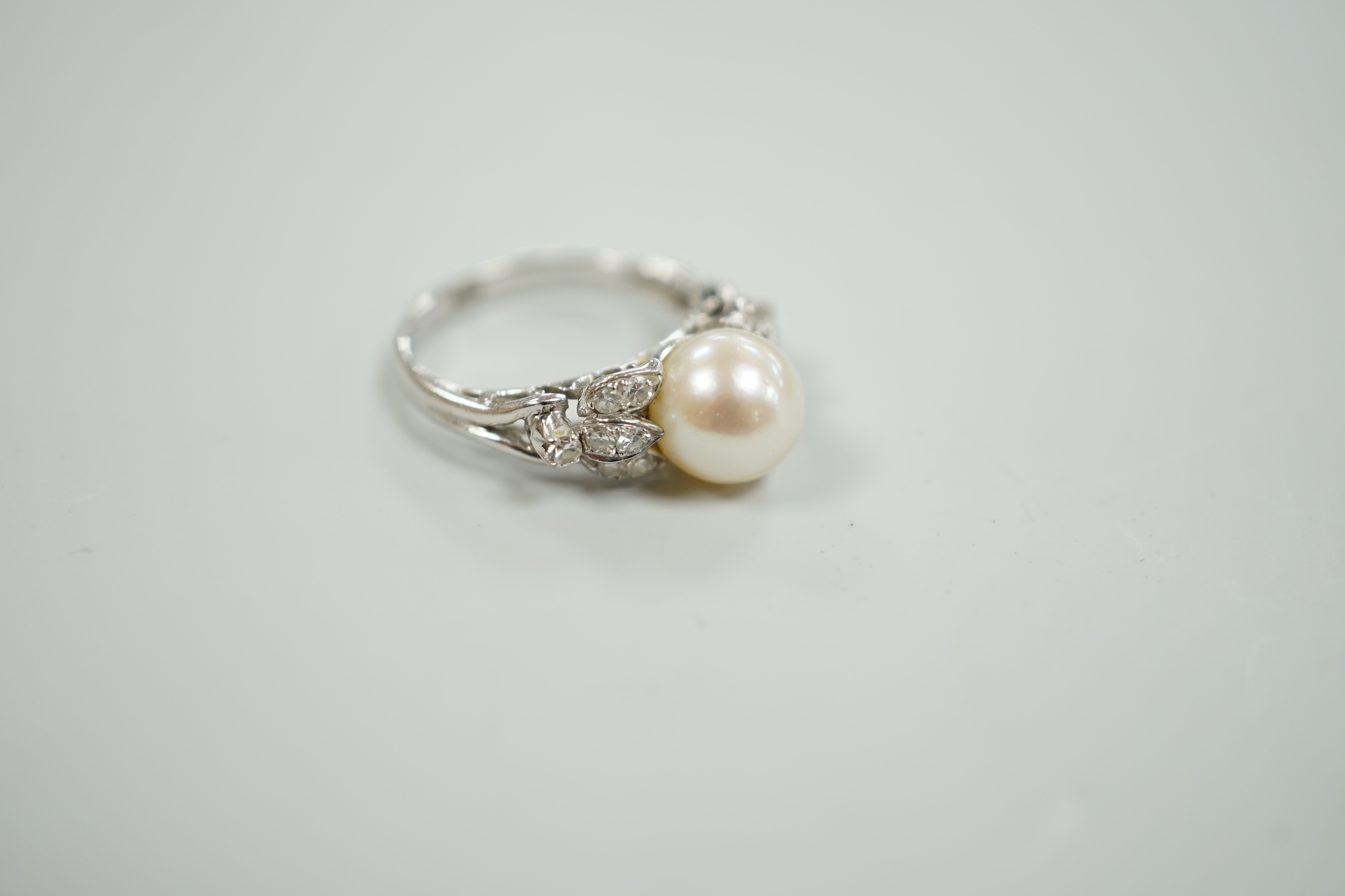 A 14k white metal and single stone cultured pearl set dress ring, with diamond cluster set shoulders, size J, gross weight 3.4 grams.